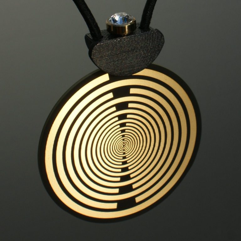 Goldene Medaille mit spiralförmigem Muster und einem weißen Stein oben eingesteckt.